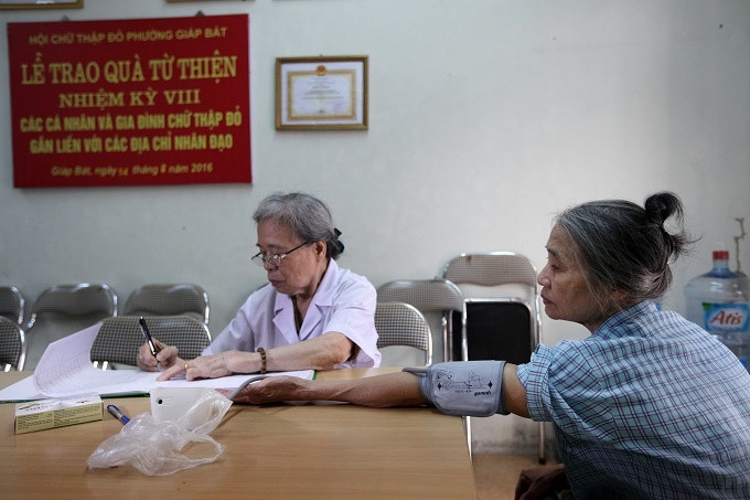 Y tá đo huyết áp cho bệnh nhân trước khi chuyển sang bác sĩ kiểm tra, khám bệnh. Bác sĩ 20 năm lấy lương hưu mở phòng khám miễn phí
