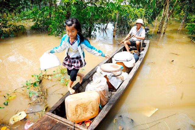 Cô bé thành thạo bước trên mạn ghe của cha để lên bờ vào trường