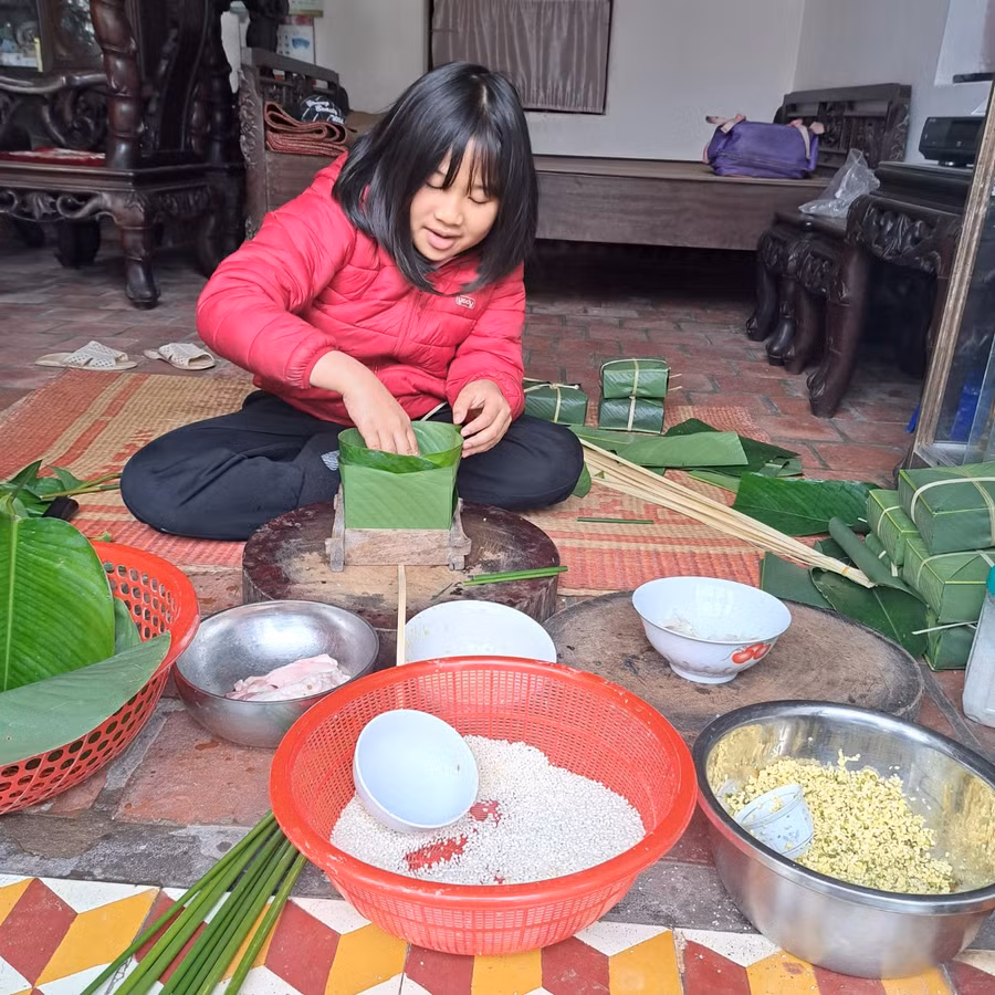 Học sinh Trường Tiểu học Hải Long ở nhà tham gia gói bánh chưng tại gia đình.