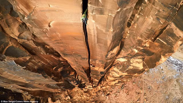 Một thanh niên nép mình trong vết nứt khe núi ở Moab, Utah, Mỹ.