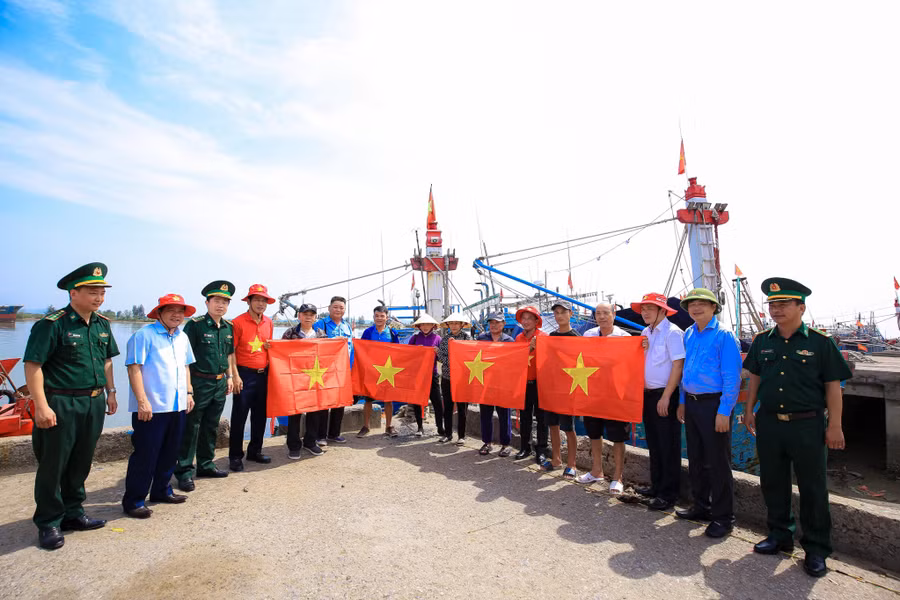 Báo Người lao động phối hợp với các Ban, ngành trao cờ Tổ quốc đến ngư dân bám biển. (Ảnh: TM).