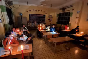 Các học viên của lớp xóa mù chữ học dưới ánh nến.