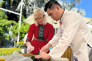 Du khách quốc tế trong trang phục truyền thống tham gia gói bánh chưng.
