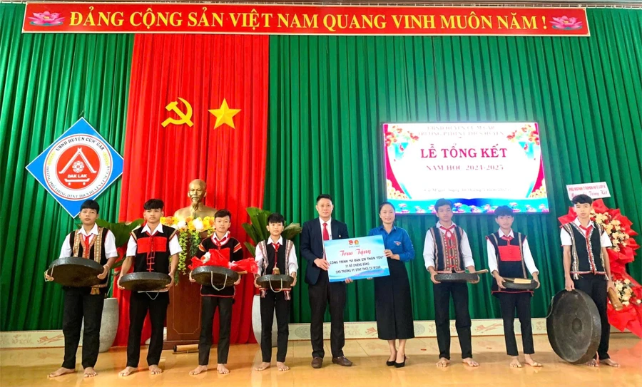 Bà Võ Thị Mỹ Trinh – Bí thư Huyện đoàn Cư M'gar trao tặng bộ cồng chiêng cho thầy và trò nhà trường. (Ảnh: TT)