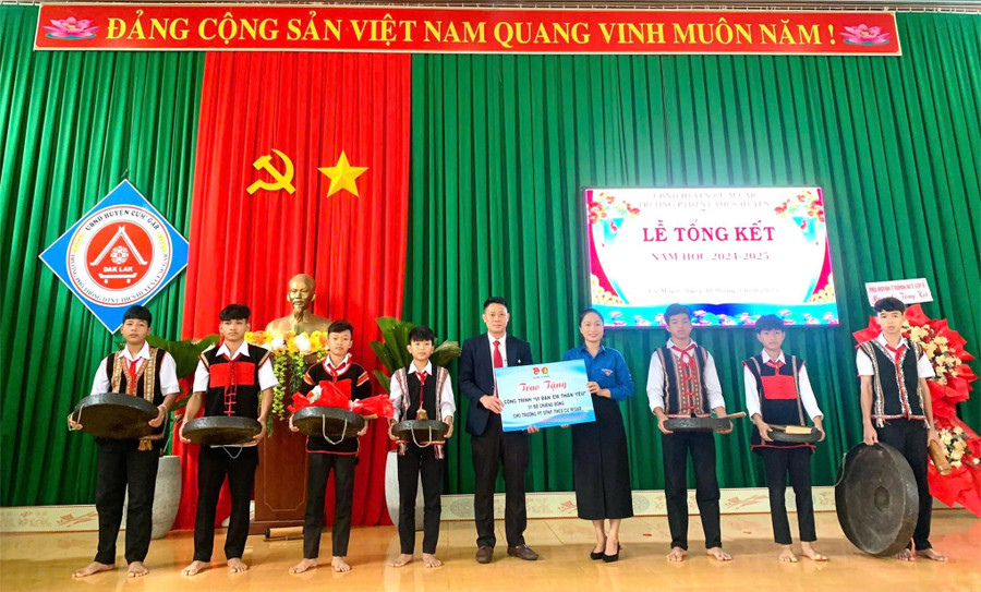 Bà Võ Thị Mỹ Trinh – Bí thư Huyện đoàn Cư M'gar trao tặng bộ cồng chiêng cho thầy và trò nhà trường. (Ảnh: TT)
