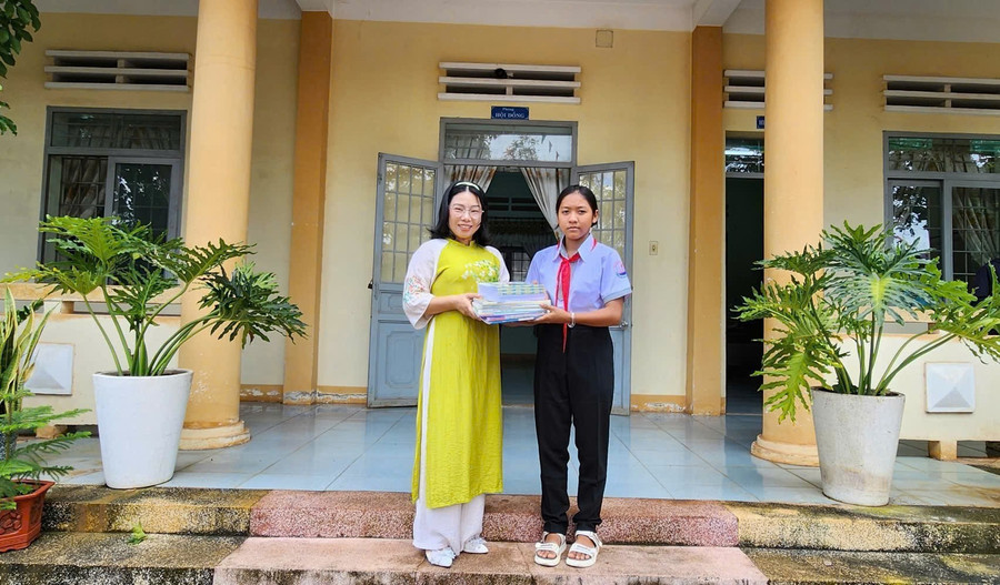 Em H' Như (chị gái của Khang) được đi học với sự hỗ trợ từ thầy cô, ngành chức năng. (Trong hình, em H' Như nhận sách, vở do đại diện Báo GD&ĐT tại Đắk Lắk gửi tặng) chi-gai.jpg
