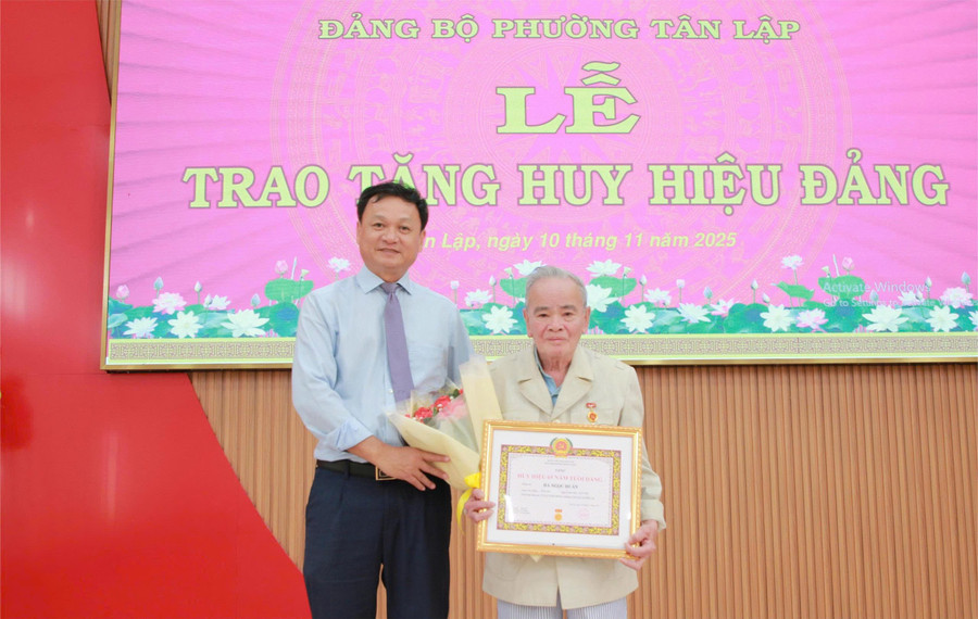 Ông Vũ Văn Hưng trao Huy hiệu 65 năm tuổi Đảng cho đảng viên Hà Học Tuấn. (Ảnh: Thành Tâm)