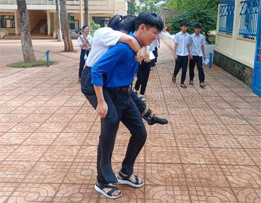 Thí sinh đến điểm thi bằng nạng được thanh niên tình nguyện cõng đến phòng thi. (Ảnh: TT)