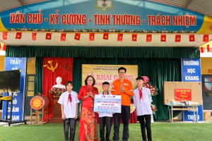 Đại diện Công ty TNHH Khai thác Chế biến Khoáng sản Núi Pháo trao quà cho các em học sinh. 