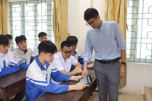 Thầy giáo chủ nhiệm hướng dẫn học sinh trường THPT Khánh Hoà thử đăng ký dự thi trực tuyến.