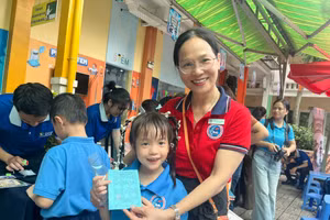Bé Gia Hân, học sinh lớp 2/6, Trường tiểu học Đinh Tiên Hoàng khoe cô giáo những trạm vui chơi mà em đã thực hiện được trong ngày hội. Ảnh: MD