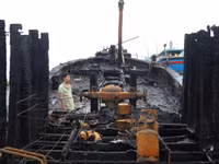 Đứng giữa xác tàu cháy đen, người ngư dân lặng người trước mất mát quá lớn.