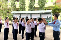 Thầy Nguyễn Chí Tài hướng dẫn học sinh tập nghi thức đội. Ảnh: Quách Mến