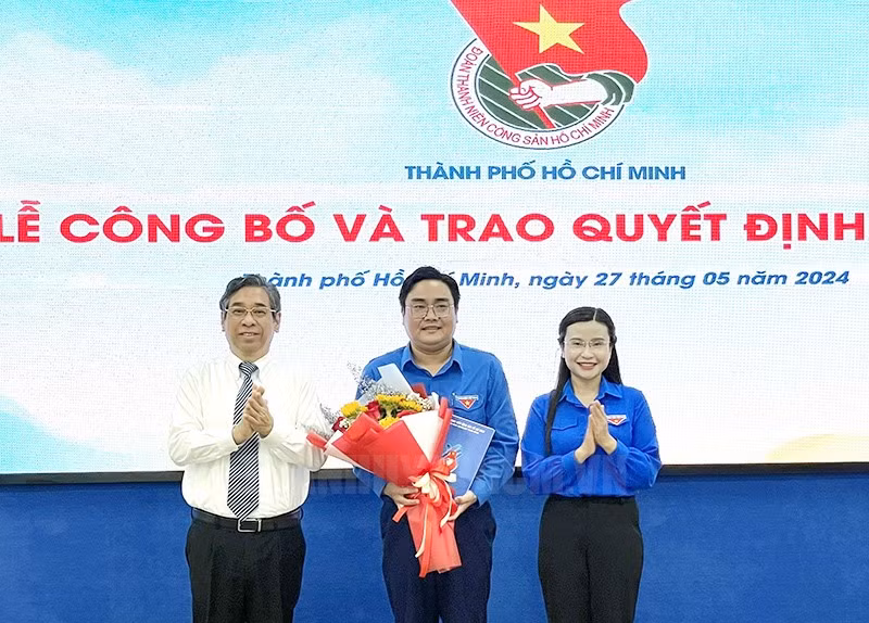 Bà Nguyễn Phạm Duy Trang trao quyết định và ông Nguyễn Phước Lộc tặng hoa chúc mừng anh Ngô Minh Hải, Bí thư Thành Đoàn TPHCM.