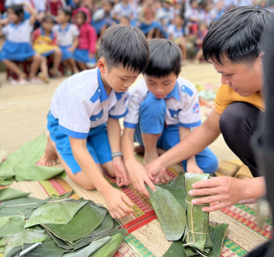Các em học sinh trải nghiệm gói bánh tét ngày Tết. Ảnh: Thanh Tú.