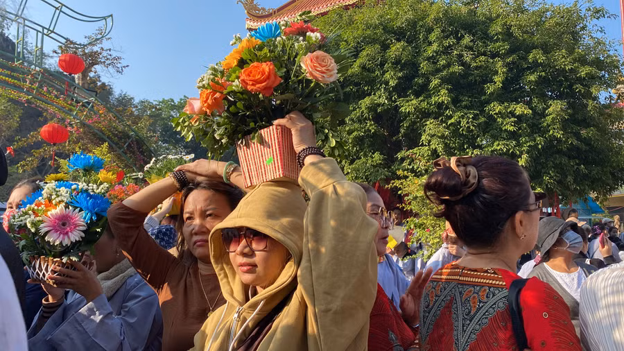 Người dân, tăng ni, phật tử đội hoa dâng lên Quán Thế Âm Bồ Tát. Ảnh: Hoàng Vinh.