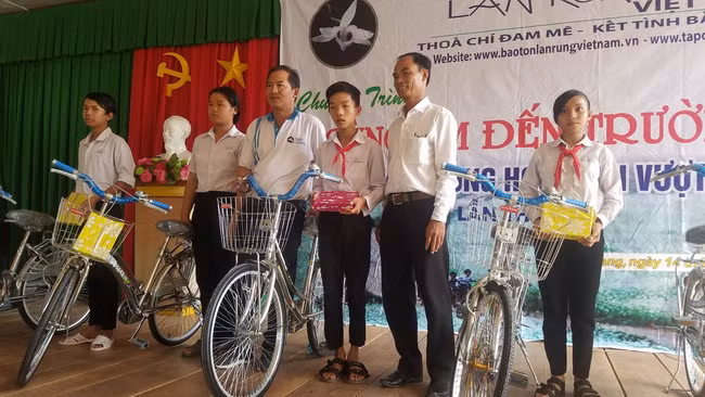 Đại diện Ban quản trị Hội Bảo tồn lan rừng Việt Nam trao tặng xe và tập cho các em học sinh