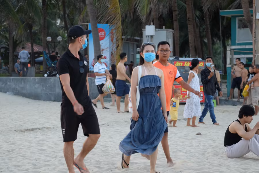 Du khách vẫn tuân thủ việc đeo khẩu trang khi xuống biển.