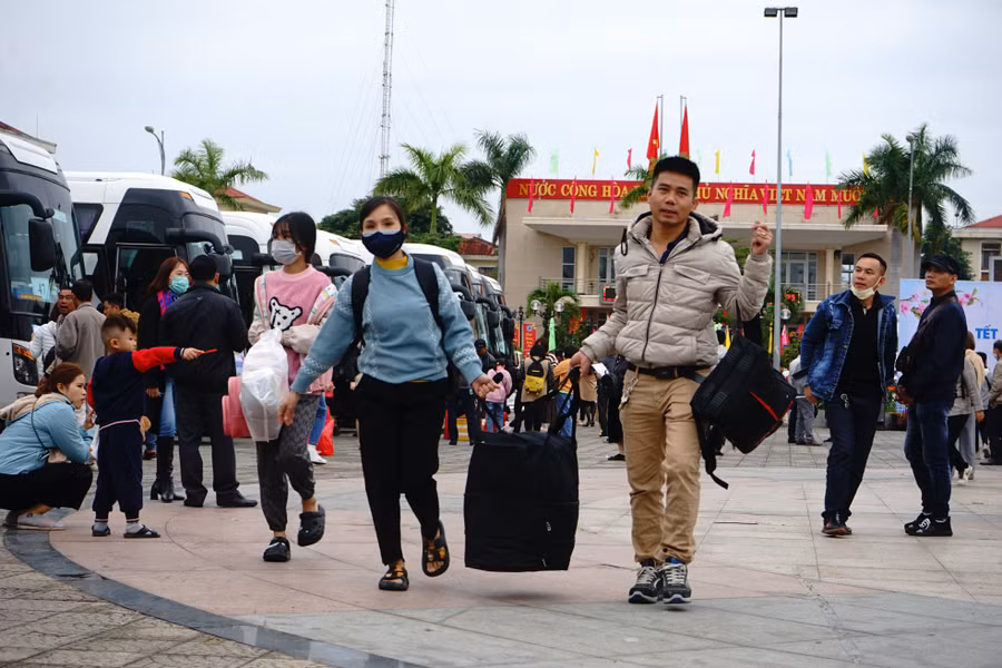 Một cặp vợ chồng mang hành lý để lên xe trở về quê đón Tết cổ truyền. Ảnh: Vinh Hoàng.