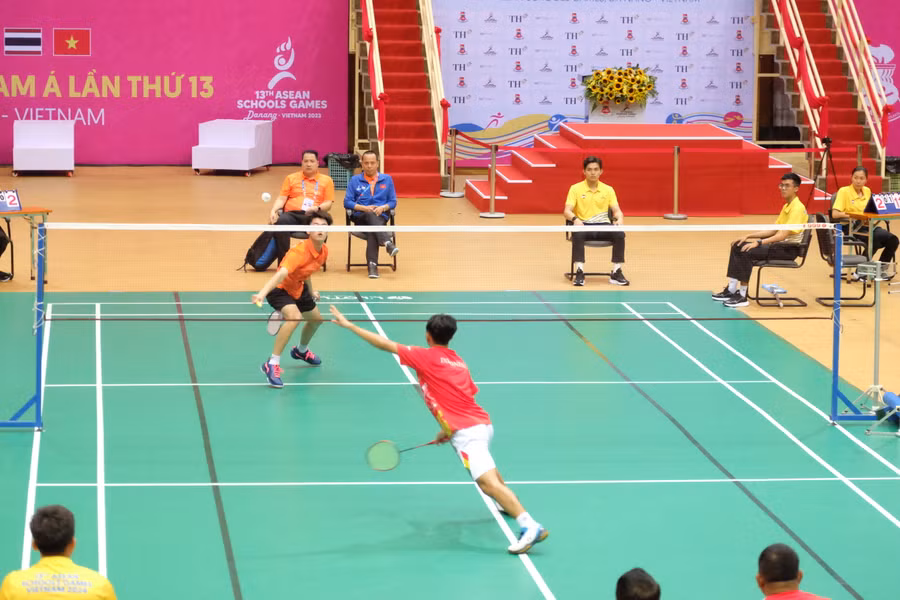 Tay vợt Lê Minh Sơn (áo cam) thi đấu với tay vợt Indonesia.