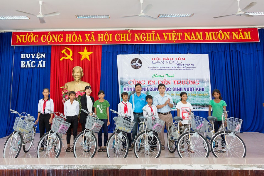 Đại diện lãnh đạo Hội Bảo tồn lan rừng Việt Nam và chính quyền địa phương trao tặng xe đạp và tập cho học sinh. (Ảnh: TL Hội)