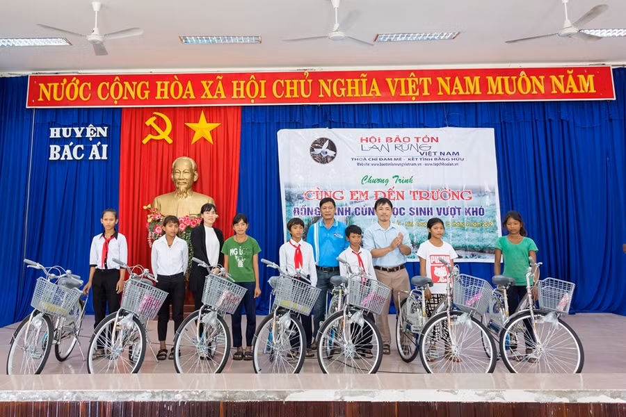 Đại diện lãnh đạo Hội Bảo tồn lan rừng Việt Nam và chính quyền địa phương trao tặng xe đạp và tập cho học sinh. (Ảnh: TL Hội)