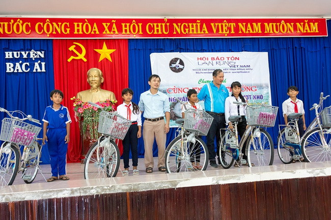 Đại diện lãnh đạo Hội Bảo tồn lan rừng Việt Nam và chính quyền địa phương trao tặng xe đạp và tập cho học sinh. (Ảnh: TL Hội)