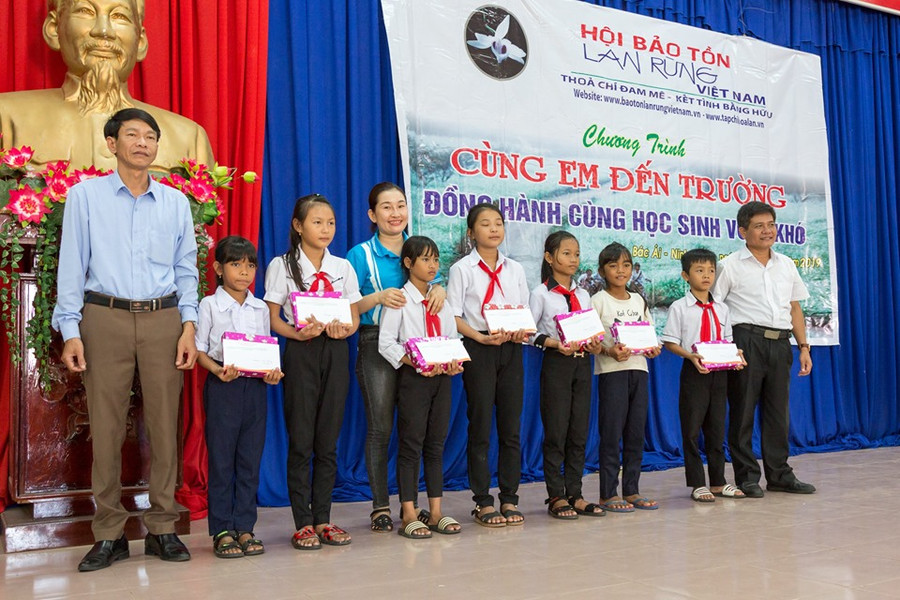 Đại diện lãnh đạo Hội Bảo tồn lan rừng Việt Nam và chính quyền địa phương trao tặng học bổng và tập cho học sinh.(Ảnh" TL Hội)