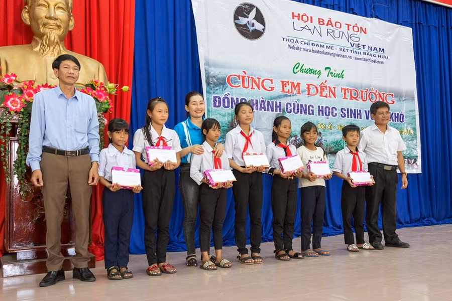 Đại diện lãnh đạo Hội Bảo tồn lan rừng Việt Nam và chính quyền địa phương trao tặng học bổng và tập cho học sinh.(Ảnh" TL Hội)