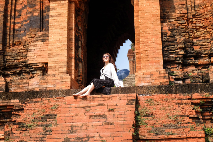 Diềm mái tháp hơi nhô ra nâng toàn bộ ba tầng mái, trang trí đơn giản nhưng khỏe khoắn. Phần móng tháp và thân tháp cách nhau một lớp đá ong. Họa tiết trang trí phần chân đế là những cột trụ kép tạc hình cánh hoa kép cách điệu đối xứng qua thân. Ảnh: Hoàng Vinh.