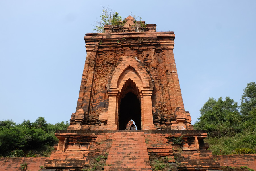 Vòm cửa chính giống hình mũi lao có nhiều lớp liên tiếp vút lên cao, hai mặt còn lại là cửa giả có kích thước và vòm được mô phỏng giống cửa thật. Quanh chân tháp có những rãnh dọc được soi lõm, tạo thành những cột ốp có dáng cao vút, thanh thoát nhẹ nhàng. Ảnh: Hoàng Vinh.