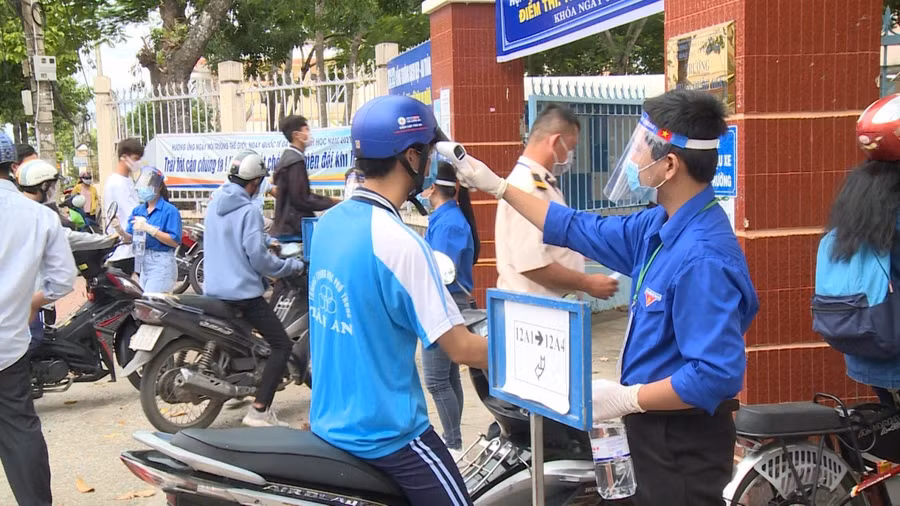 Các tình nguyện viên đo thân nhiệt và sát khuẩn tay cho thí sinh trước khi đến điểm thi (Ảnh: Ngọc Thạch)