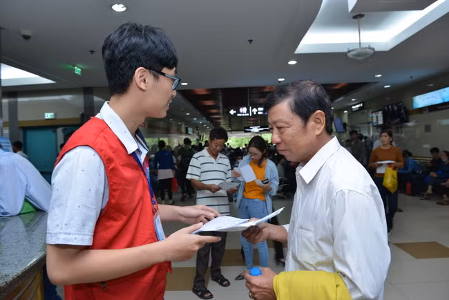 Áo đỏ tình nguyện hướng dẫn bệnh nhân đến vị trí phòng khám ( Ảnh: BVCC)