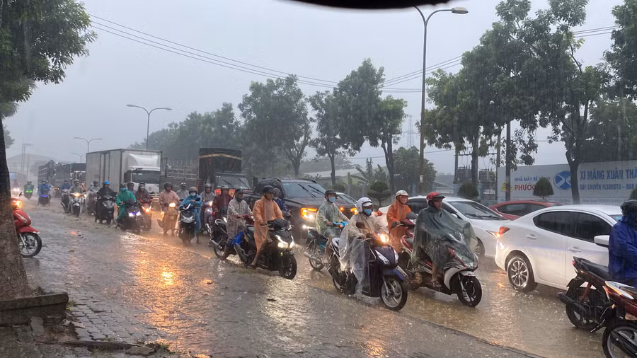 Xe máy và ô tô xếp hàng dài qua đoạn ngập nước. (Ảnh: Hoàng Vinh)