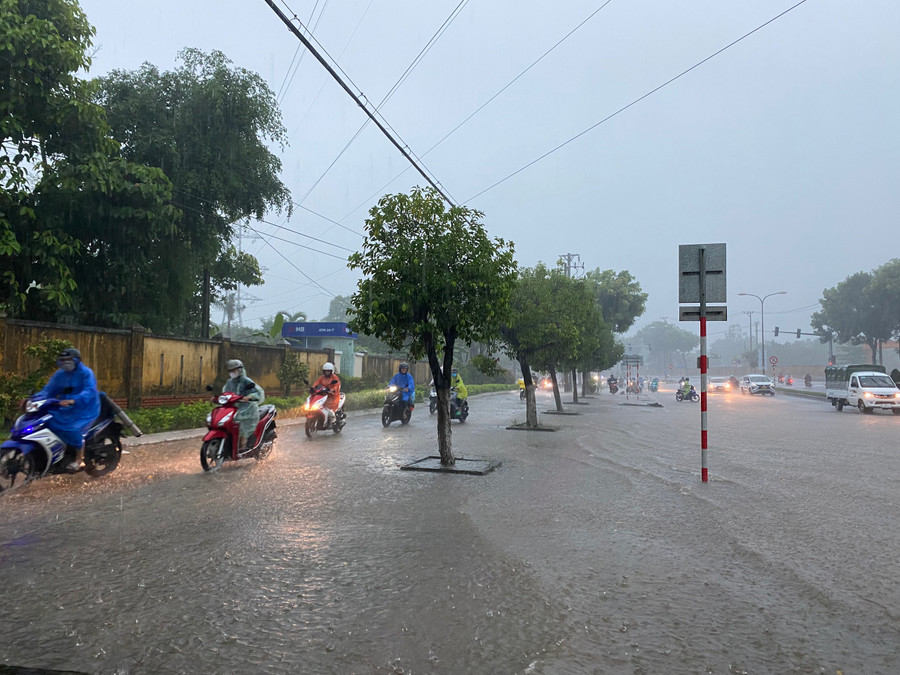 Nhiều người đi xe máy phải chạy trên vỉa hè để tránh ngập nước. (Ảnh: Hoàng Vinh)