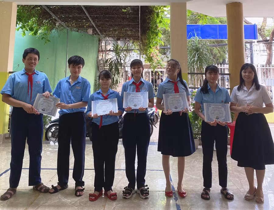 Cô Hà trao giấy khen cho học sinh.