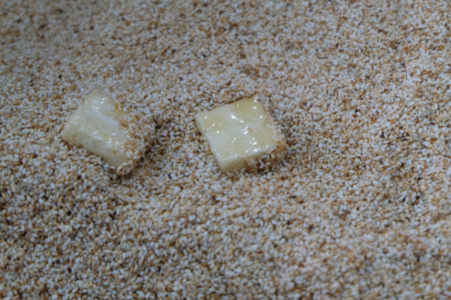 Bánh sau khi nhúng qua đường mía sẽ được lăn qua mè.