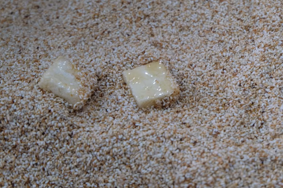 Bánh sau khi nhúng qua đường mía sẽ được lăn qua mè. Bánh sau khi nhúng qua đường mía sẽ được lăn qua mè.