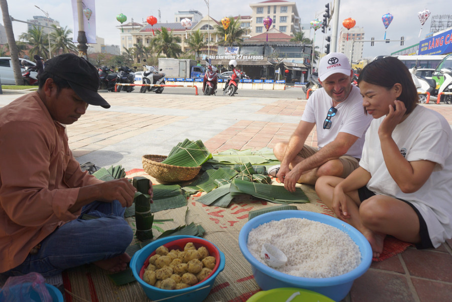 Đến với chương trình, du khách có cơ hội trải nghiệm nấu bánh chưng, bánh tét, tự làm các loại bánh mứt cổ truyền như bánh in, bánh thuẫn, mứt dừa… Trong ảnh, du khách nước ngoài chuẩn bị gói bánh tét dưới sự hướng dẫn của các nghệ nhân.