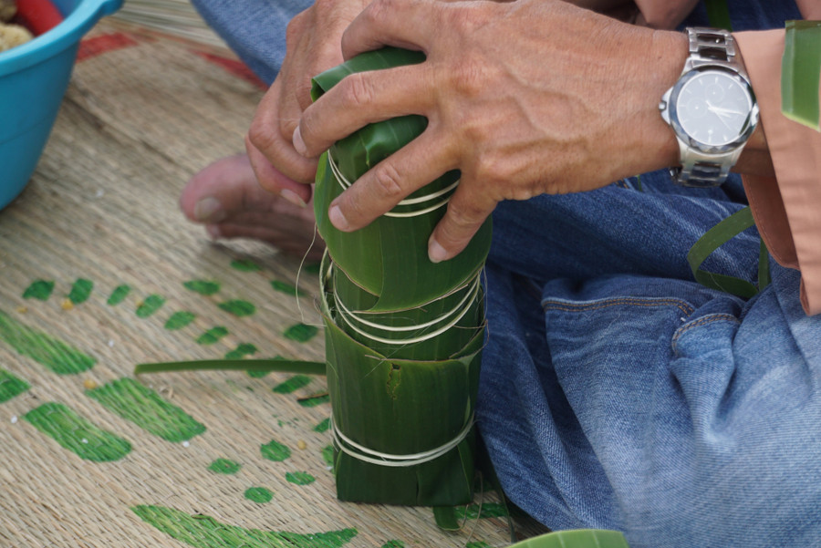 Nghệ nhân hướng dẫn tỉ mỉ cho du khách gói bánh.