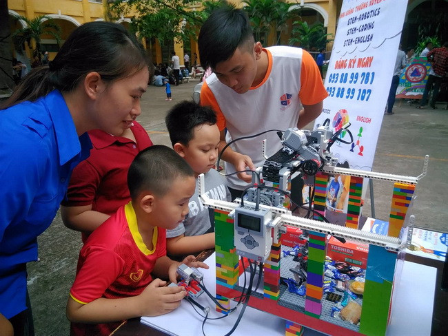 Các em học sinh hào hứng trải nghiệm các hoạt động khoa học và trò chơi robot gắp đồ vật.