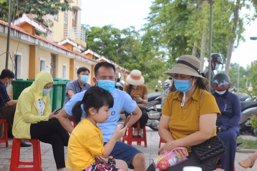 Gia đình chị Cao Thị Văn ngồi ngoài điểm thi đợi con hoàn thành bài thi.