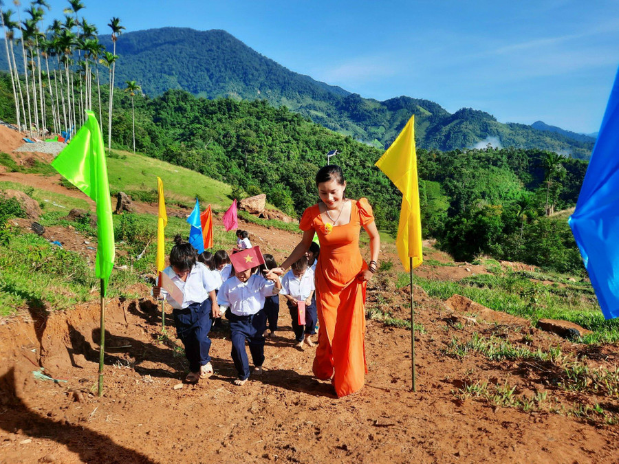 Cô giáo Trà Thị Thu trong trang phục áo dài, dắt các em học sinh đến trường. Cô giáo Trà Thị Thu trong trang phục áo dài, dắt các em học sinh đến trường.