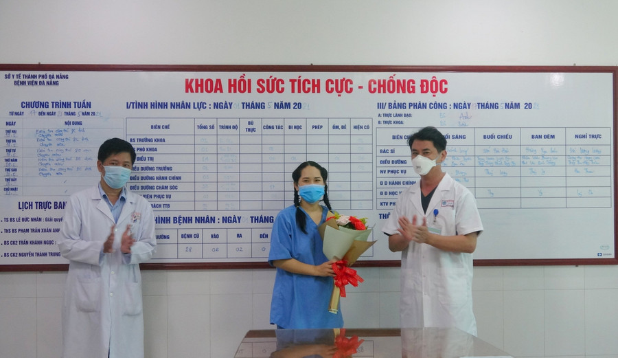 Bác sĩ Lê Đức Nhân (bìa phải) - Giám đốc bệnh viện Đà Nẵng và bác sĩ Nguyễn Thành Trung (bìa trái - PGĐ Bệnh viện tặng hoa cho nữ điều dưỡng. 