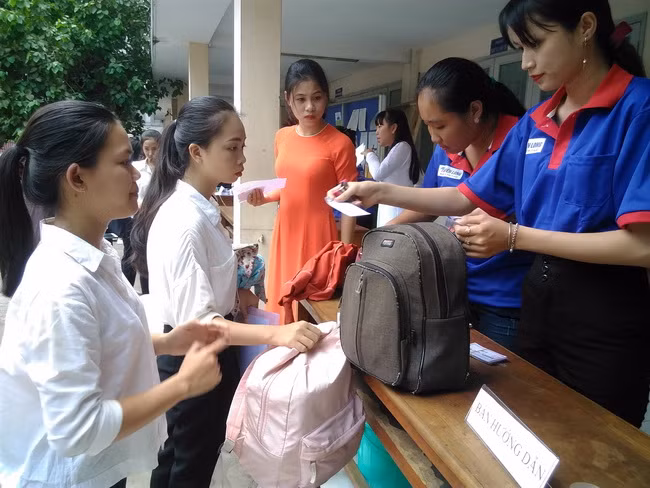 Thí sinh được các tình nguyện viên hướng dẫn và cất giữ đồ tư trang trước khi vào phòng thi.