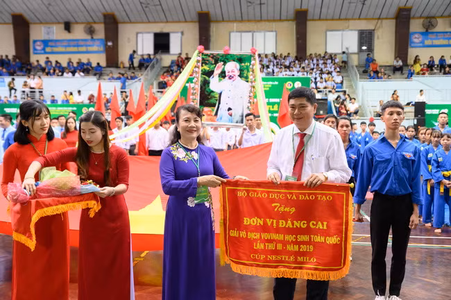 Thứ trưởng Bộ GD&ĐT Nguyễn Thị Nghĩa trao cờ lưu niệm cho Ông Phạm Đăng Khoa -GĐ Sở GD&ĐT Đắk Lắk đơn vị đăng cai giải đấu.( Ảnh: Ban tổ chức)