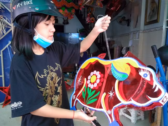 Một học sinh đến chọn mua mẫu lồng đèn hình chú heo Đông Hồ rất đẹp mắt để về vui Trung thu tại trường. Đây là mẫu mới cho mùa Trung thu năm nay do cơ sở của gia đình anh Bình sản xuất.