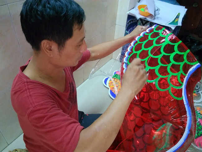 Anh Nguyễn Trọng Thành đang vẽ màu trang trí phần thân cho chiếc lồng đèn con rồng.