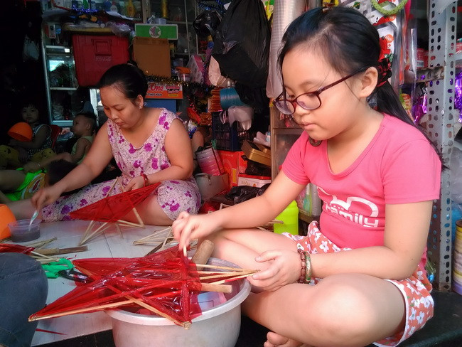 Em Nguyễn Thanh Hạ, học sinh lớp 3 trường TH Lê Thành Tông Quận Tân Phú TPHCM trải nghiệm công việc dán giấy và vẽ trên lồng đèn ông sao.