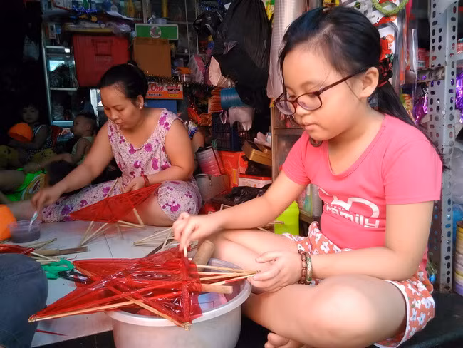 Em Nguyễn Thanh Hạ, học sinh lớp 3 trường TH Lê Thành Tông Quận Tân Phú TPHCM trải nghiệm công việc dán giấy và vẽ trên lồng đèn ông sao.